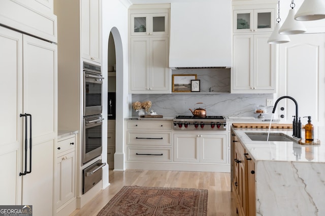 900 Crabapple Hl, Milton, GA 30004 - kitchen featuring a warming drawer, appliances with stainless steel finishes, a sink, wall chimney exhaust hood, and light wood finished floors