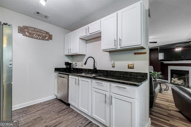 907 Magnolia Ext, Guyton, GA 31312 - kitchen featuring dishwasher, a sink, wood finished floors, a textured ceiling, and white cabinetry