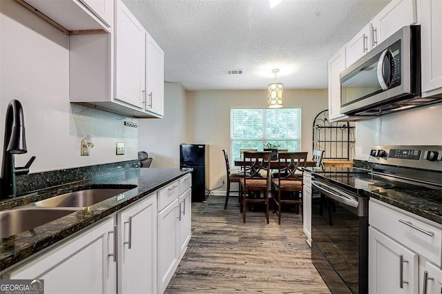 907 Magnolia Ext, Guyton, GA 31312 - kitchen featuring stainless steel microwave, electric range, a sink, wood finished floors, and white cabinetry