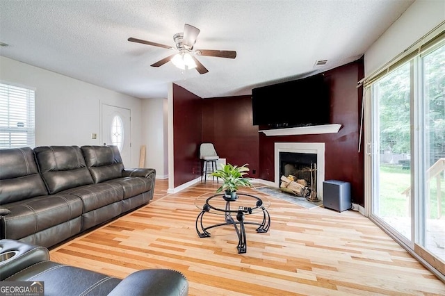 907 Magnolia Ext, Guyton, GA 31312 - living room featuring wood finished floors, ceiling fan, a textured ceiling, a fireplace with flush hearth, and baseboards
