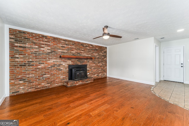 4124 W Rd, Blackshear, GA 31516 - unfurnished living room featuring a ceiling fan, wood finished floors, a wood stove, baseboards, and a textured ceiling
