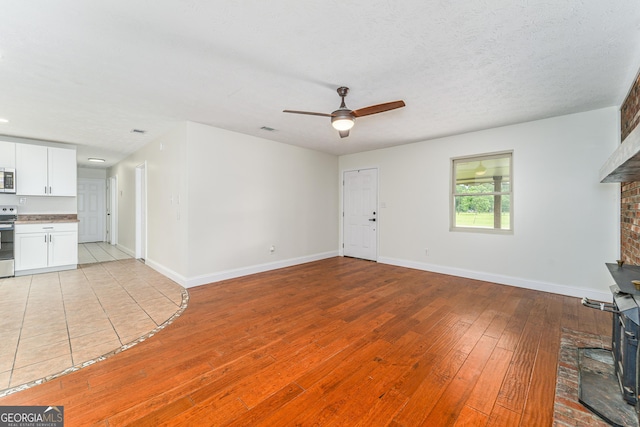 4124 W Rd, Blackshear, GA 31516 - unfurnished living room featuring ceiling fan, light wood finished floors, baseboards, and a brick fireplace