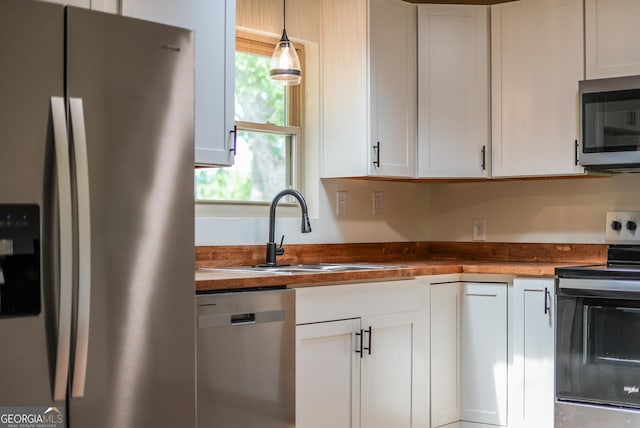 4124 W Rd, Blackshear, GA 31516 - kitchen with stainless steel appliances, a sink, white cabinets, decorative light fixtures, and wooden counters