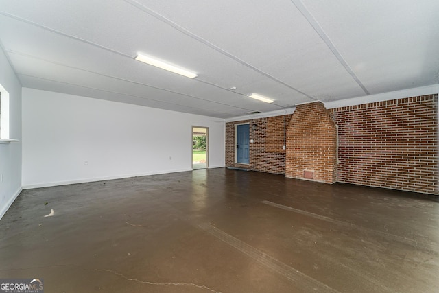 4124 W Rd, Blackshear, GA 31516 - unfurnished living room featuring finished concrete flooring, brick wall, and baseboards