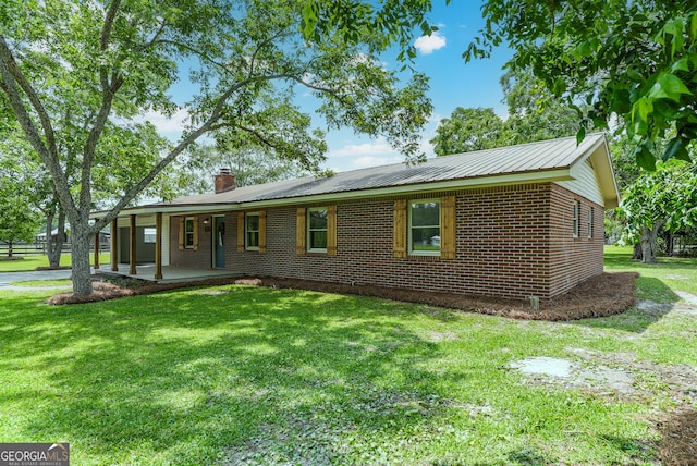 4124 W Rd, Blackshear, GA 31516 - view of front facade with a chimney, brick siding, a front yard, and metal roof