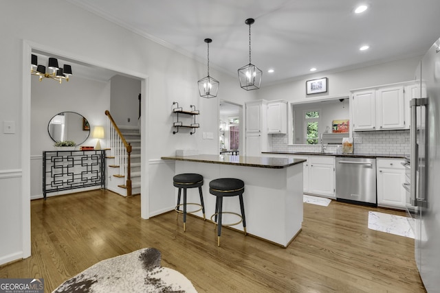 305 River Glen Dr, Roswell, GA 30075 - kitchen featuring stainless steel appliances, crown molding, a peninsula, wood finished floors, and white cabinetry