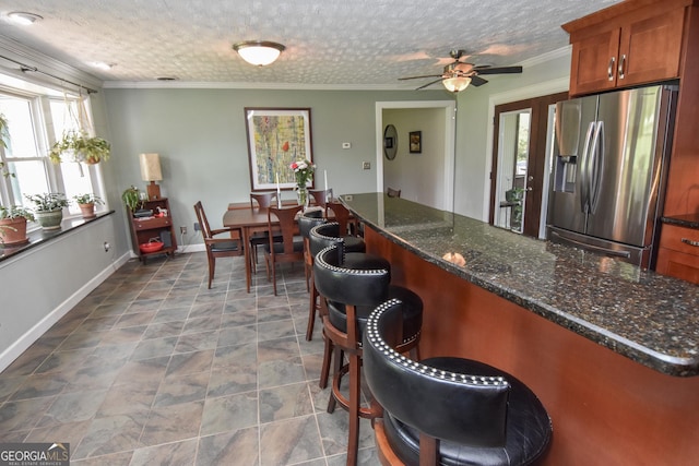 2048 Swint Rd, Griffin, GA 30224 - kitchen with stainless steel fridge with ice dispenser, brown cabinets, ceiling fan, crown molding, and a kitchen bar