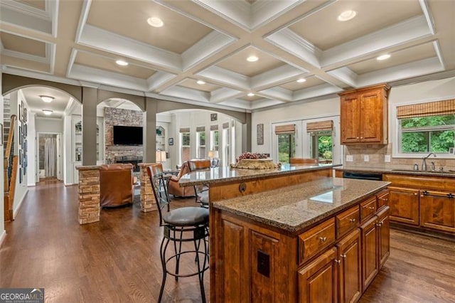 9065 Yellow Pine Ct, Gainesville, GA 30506 - kitchen with arched walkways, a kitchen bar, brown cabinets, a kitchen island, and coffered ceiling