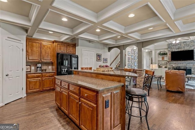 9065 Yellow Pine Ct, Gainesville, GA 30506 - kitchen featuring black fridge with ice dispenser, a breakfast bar, dark wood finished floors, brown cabinets, and coffered ceiling