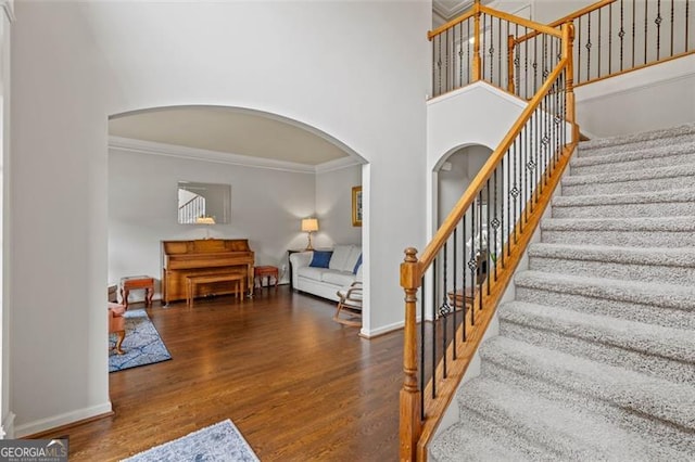 9065 Yellow Pine Ct, Gainesville, GA 30506 - stairs featuring arched walkways, crown molding, wood finished floors, and a high ceiling