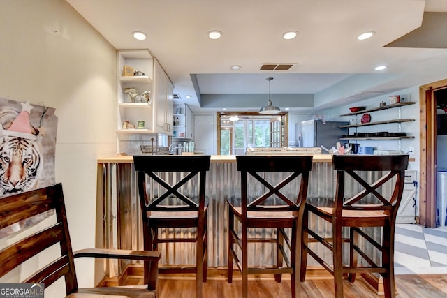 1365 Lower Creighton Rd, Cumming, GA 30028 - bar featuring freestanding refrigerator, a raised ceiling, recessed lighting, light floors, and pendant lighting