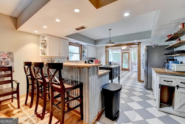 1365 Lower Creighton Rd, Cumming, GA 30028 - kitchen with open shelves, light flooring, white cabinets, a kitchen bar, and a peninsula