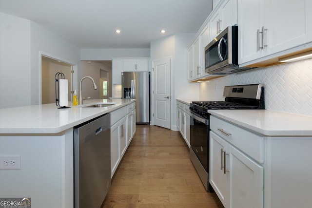 740 Pineberry Ct, Grayson, GA 30017 - kitchen with appliances with stainless steel finishes, tasteful backsplash, light wood-style flooring, a kitchen island with sink, and white cabinets