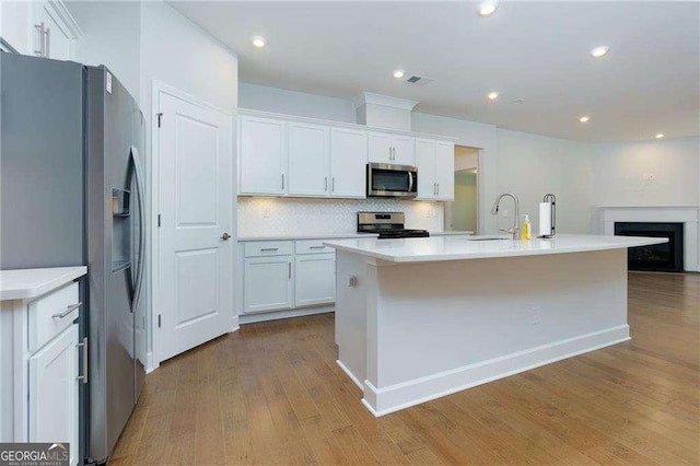 740 Pineberry Ct, Grayson, GA 30017 - kitchen with appliances with stainless steel finishes, wood finished floors, white cabinets, backsplash, and a kitchen island with sink