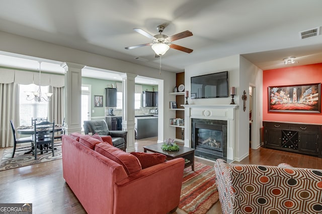 3393 Sardis Bend Dr, Buford, GA 30519 - living area with a chandelier, a ceiling fan, a glass covered fireplace, decorative columns, and dark wood finished floors