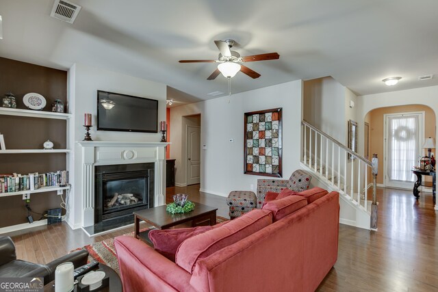 3393 Sardis Bend Dr, Buford, GA 30519 - living area with wood finished floors, arched walkways, a glass covered fireplace, a ceiling fan, and stairway