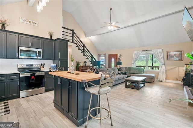 76 Beech Creek Cir, Winder, GA 30680 - kitchen featuring stainless steel appliances, wood counters, open floor plan, a breakfast bar, and ceiling fan