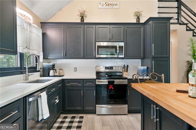 76 Beech Creek Cir, Winder, GA 30680 - kitchen featuring appliances with stainless steel finishes, a sink, butcher block counters, light wood-style flooring, and decorative backsplash