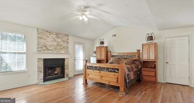 475 Cascade Rise Ct, South Fulton, GA 30331 - bedroom featuring vaulted ceiling, wood finished floors, a textured ceiling, and a stone fireplace
