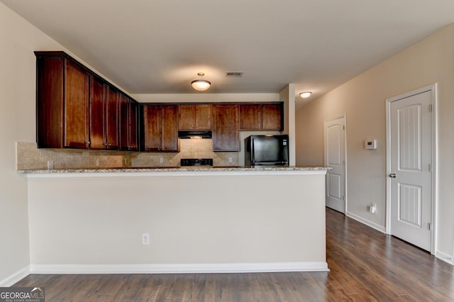 5831 Taka Ln, Lithonia, GA 30038 - kitchen with freestanding refrigerator, under cabinet range hood, backsplash, light stone counters, and a peninsula