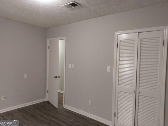 2566 Stratford Ln, Morrow, GA 30260 - unfurnished bedroom featuring dark wood-style flooring, a closet, a textured ceiling, and baseboards