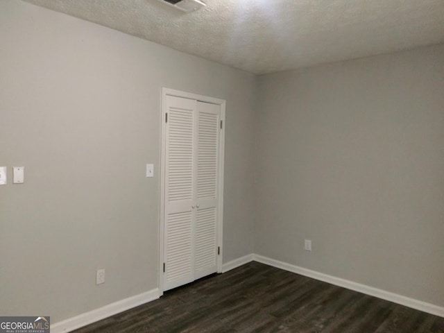 2566 Stratford Ln, Morrow, GA 30260 - unfurnished bedroom featuring baseboards, dark wood-style flooring, a closet, and a textured ceiling