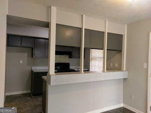2566 Stratford Ln, Morrow, GA 30260 - kitchen featuring black range with electric cooktop, a peninsula, under cabinet range hood, a textured ceiling, and light countertops