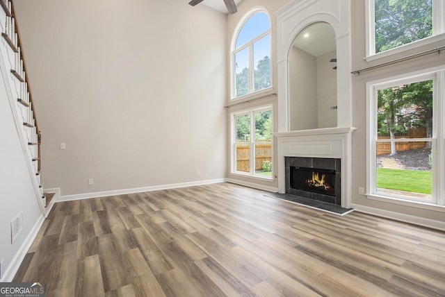 300 Windsor Chase Trl, Johns Creek, GA 30097 - unfurnished living room featuring a towering ceiling, wood finished floors, a lit fireplace, stairs, and baseboards