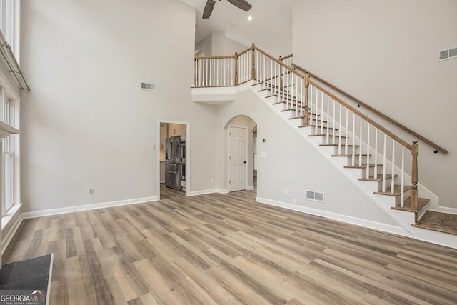 300 Windsor Chase Trl, Johns Creek, GA 30097 - unfurnished living room featuring a ceiling fan, stairway, arched walkways, high vaulted ceiling, and wood finished floors