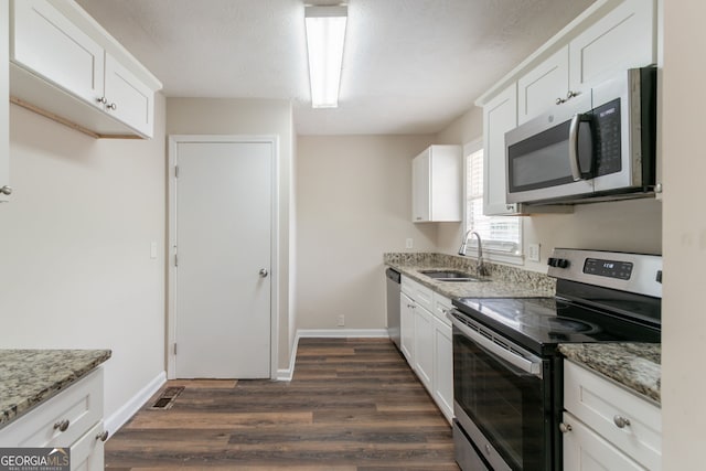 933 Capitol View Ave NW, Atlanta, GA 30318 - kitchen with appliances with stainless steel finishes, dark wood finished floors, light stone counters, and white cabinetry