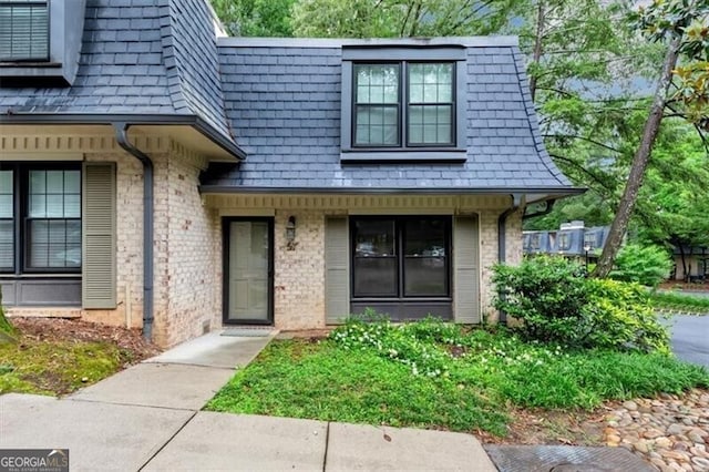 57 Cantey Pl NW, Atlanta, GA 30327 - view of exterior entry with mansard roof, brick siding, roof with shingles, and a porch