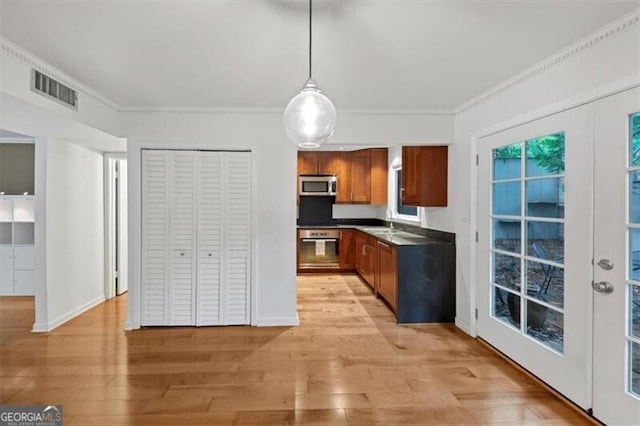 57 Cantey Pl NW, Atlanta, GA 30327 - kitchen with stainless steel microwave, brown cabinetry, ornamental molding, wall oven, and light wood finished floors