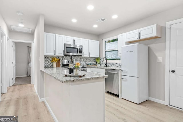 390 Lincoln Pl SW, Atlanta, GA 30315 - kitchen featuring stainless steel appliances, white cabinetry, light wood-style flooring, a peninsula, and recessed lighting