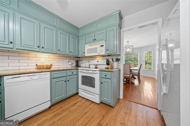 4458 Trickum Rd, Marietta, GA 30066 - kitchen featuring white appliances, light wood-type flooring, a chandelier, decorative backsplash, and light stone counters