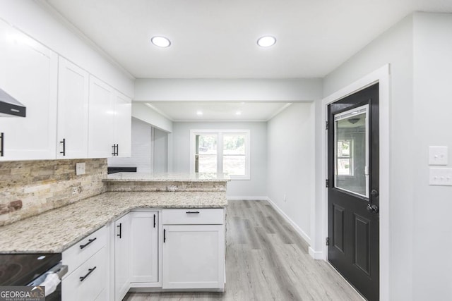 1017 Oak Ridge Dr, Byron, GA 31008 - kitchen with white cabinetry, light wood finished floors, a peninsula, backsplash, and light stone countertops