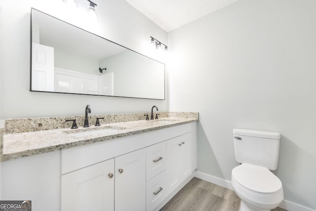 1017 Oak Ridge Dr, Byron, GA 31008 - bathroom featuring double vanity, baseboards, wood finished floors, and toilet