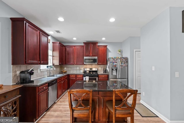 154 Stephens Mill Dr, Dallas, GA 30157 - kitchen with reddish brown cabinets, appliances with stainless steel finishes, light wood-style floors, decorative backsplash, and dark stone countertops