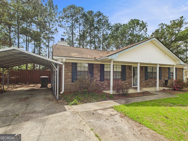 292 Whitetail Cir, Hinesville, GA 31313 - view of front of home featuring a detached carport, concrete driveway, a chimney, brick siding, and a porch