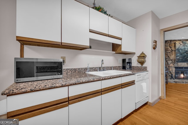 327 Brucken Strasse Unit 609, Helen, GA 30545 - kitchen featuring white dishwasher, stainless steel microwave, a sink, a stone fireplace, and light wood-type flooring