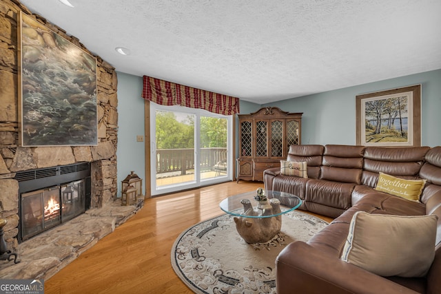 327 Brucken Strasse Unit 609, Helen, GA 30545 - living room featuring a textured ceiling, wood finished floors, and a stone fireplace