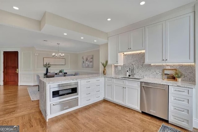 750 Park Ave NE Unit 6E, Atlanta, GA 30326 - kitchen featuring stainless steel dishwasher, a warming drawer, a chandelier, white cabinetry, and a peninsula
