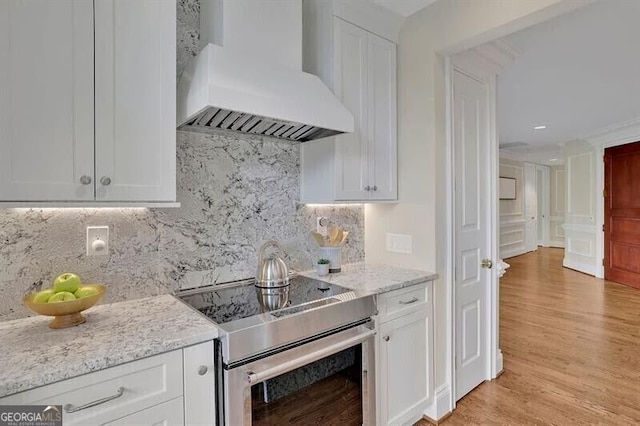 750 Park Ave NE Unit 6E, Atlanta, GA 30326 - kitchen with custom range hood, electric stove, white cabinetry, light wood-style floors, and recessed lighting