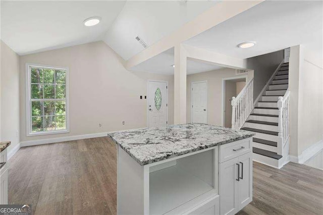 2158 Huckleberry Ln, Lithia Springs, GA 30122 - kitchen featuring vaulted ceiling, baseboards, wood finished floors, light stone countertops, and white cabinets