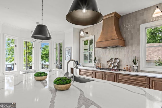 117 W View Way, Eatonton, GA 31024 - kitchen with custom exhaust hood, brown cabinets, stainless steel gas cooktop, light stone counters, and decorative backsplash
