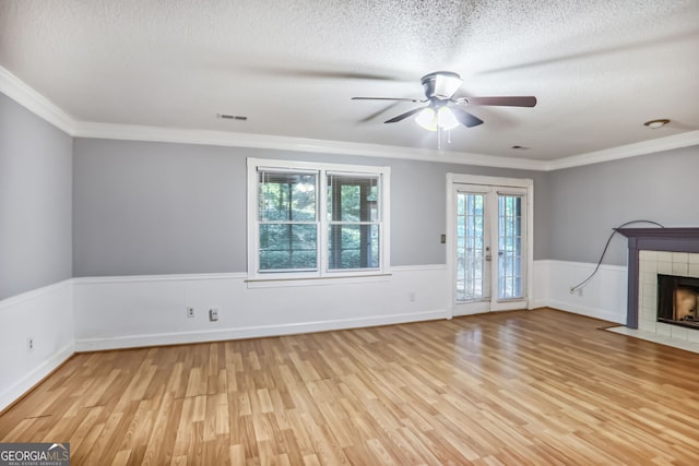 1417 Poplar Pointe SE, Smyrna, GA 30082 - unfurnished living room featuring light wood-type flooring, a ceiling fan, crown molding, a textured ceiling, and a tiled fireplace