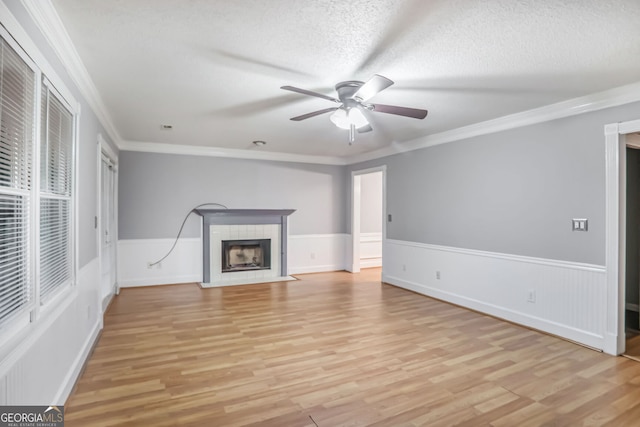 1417 Poplar Pointe SE, Smyrna, GA 30082 - unfurnished living room featuring a ceiling fan, light wood-style flooring, a tiled fireplace, crown molding, and a textured ceiling