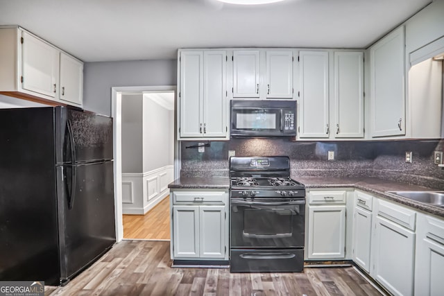 1417 Poplar Pointe SE, Smyrna, GA 30082 - kitchen featuring black appliances, white cabinets, wood finished floors, dark countertops, and wainscoting