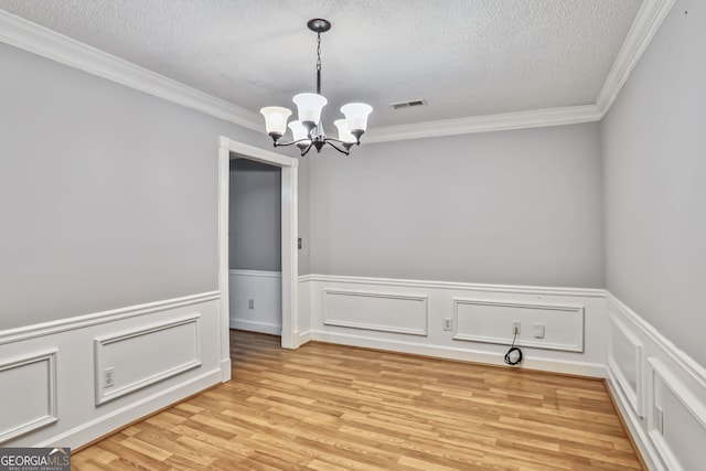 1417 Poplar Pointe SE, Smyrna, GA 30082 - unfurnished dining area with a chandelier, a textured ceiling, light wood-type flooring, ornamental molding, and a wainscoted wall