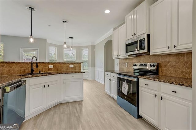 766 Chapman St, Jonesboro, GA 30238 - kitchen featuring appliances with stainless steel finishes, a sink, light wood-style flooring, arched walkways, and white cabinets