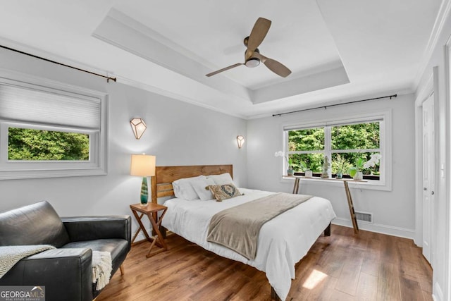 14905 Thompson Rd, Milton, GA 30004 - bedroom with multiple windows, a tray ceiling, wood finished floors, baseboards, and crown molding